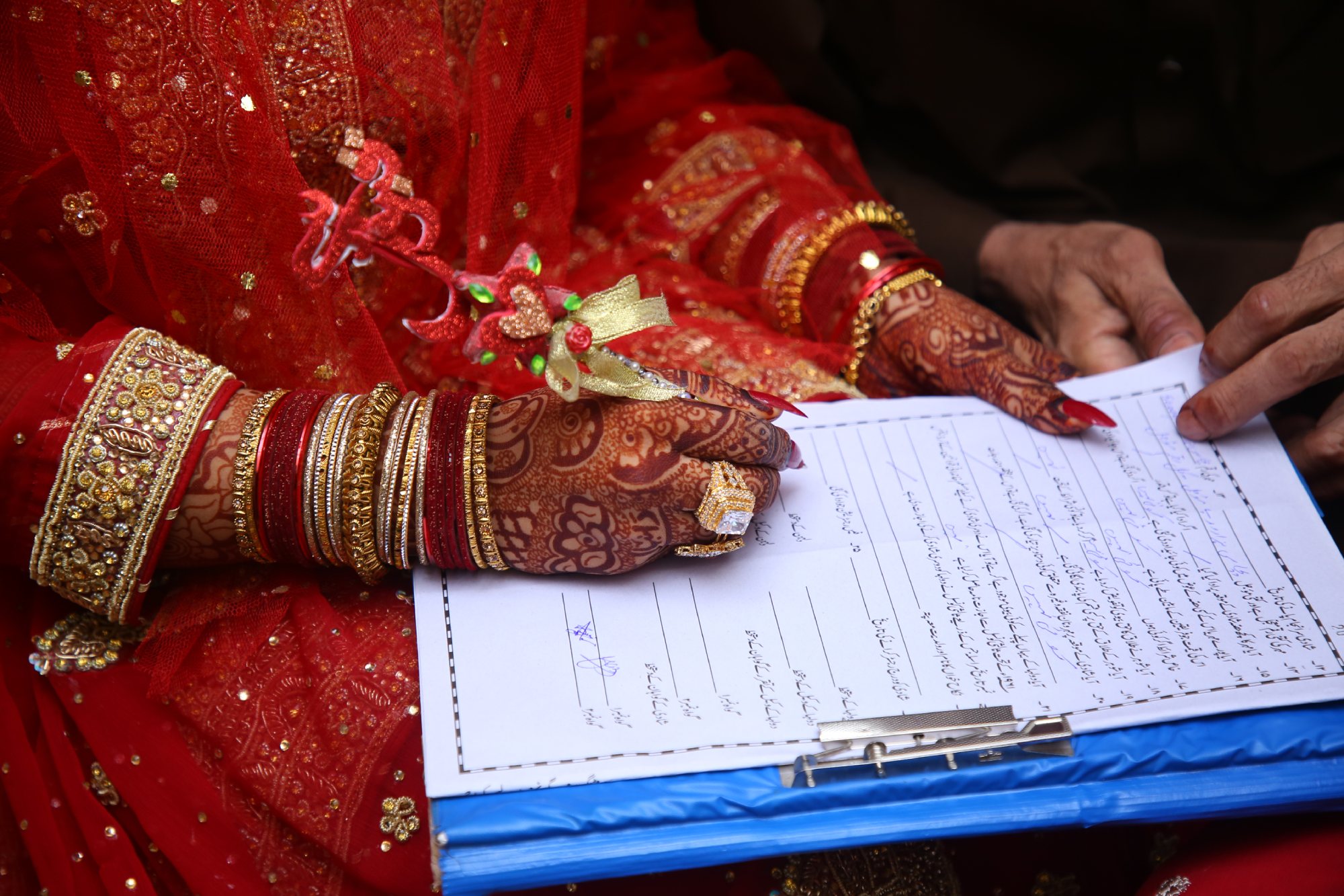 A bride and groom signing the Nikah Nama [Alt Text: A couple signing the Nikah Nama in Pakistan